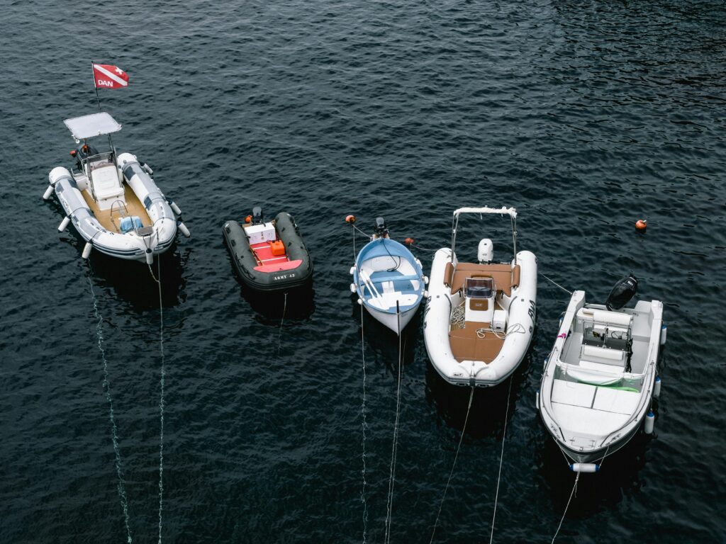Aerial shot of five boats anchored on a serene body of water, showcasing nautical tranquility.