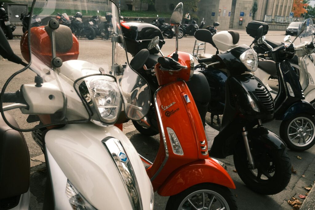 Row of vibrant scooters parked outdoors in an urban area, showcasing modern design.